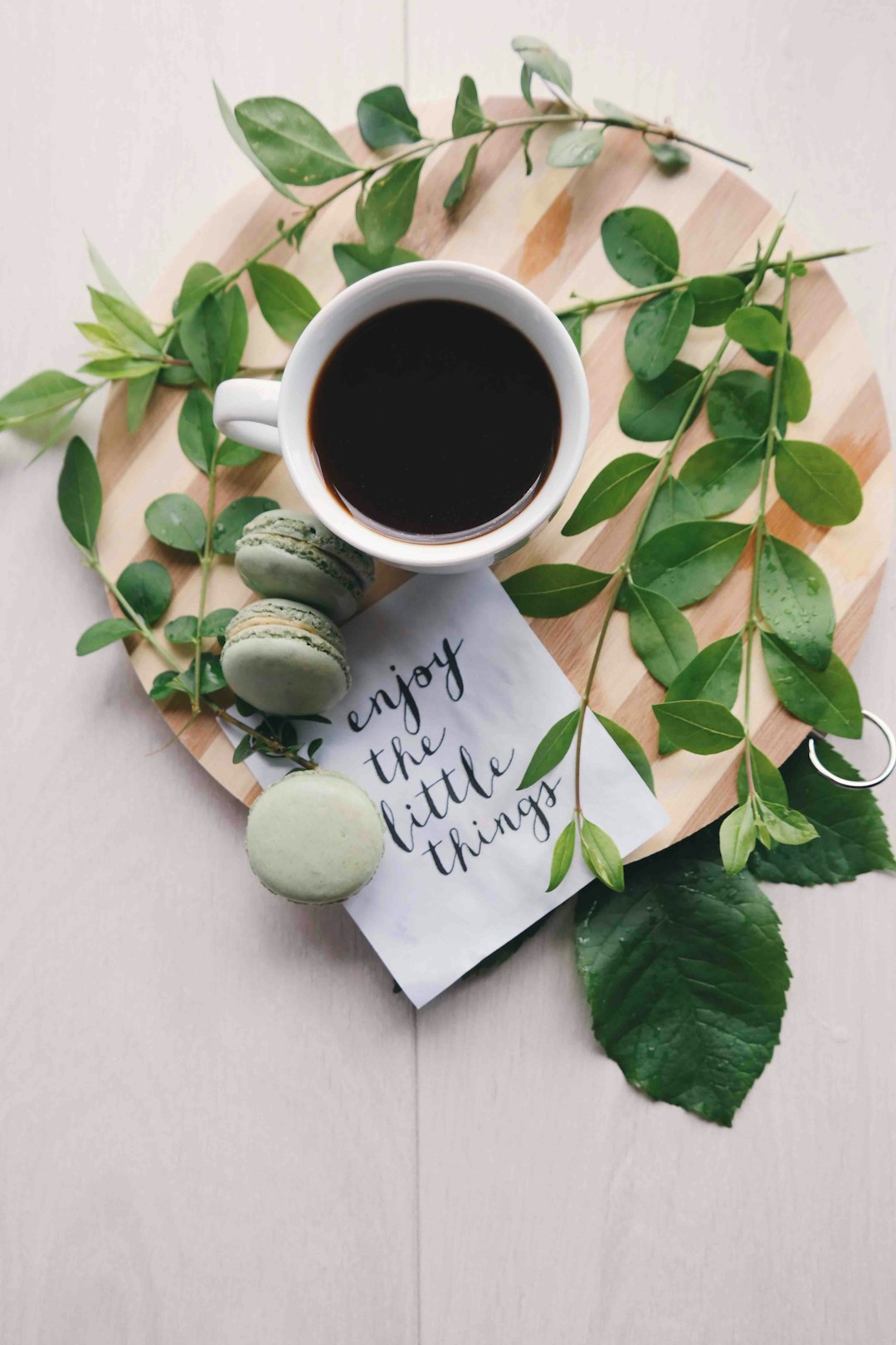 flat-lay-photography-of-leaves-with-cup-of-coffee-and-three-macarons-on-chopping-board-eaay7aj4jbc
